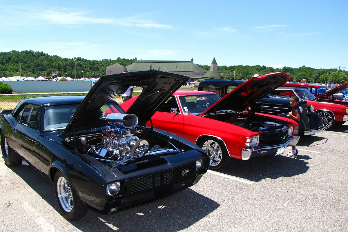 Muscle car club show with hoods up displaying classic engines